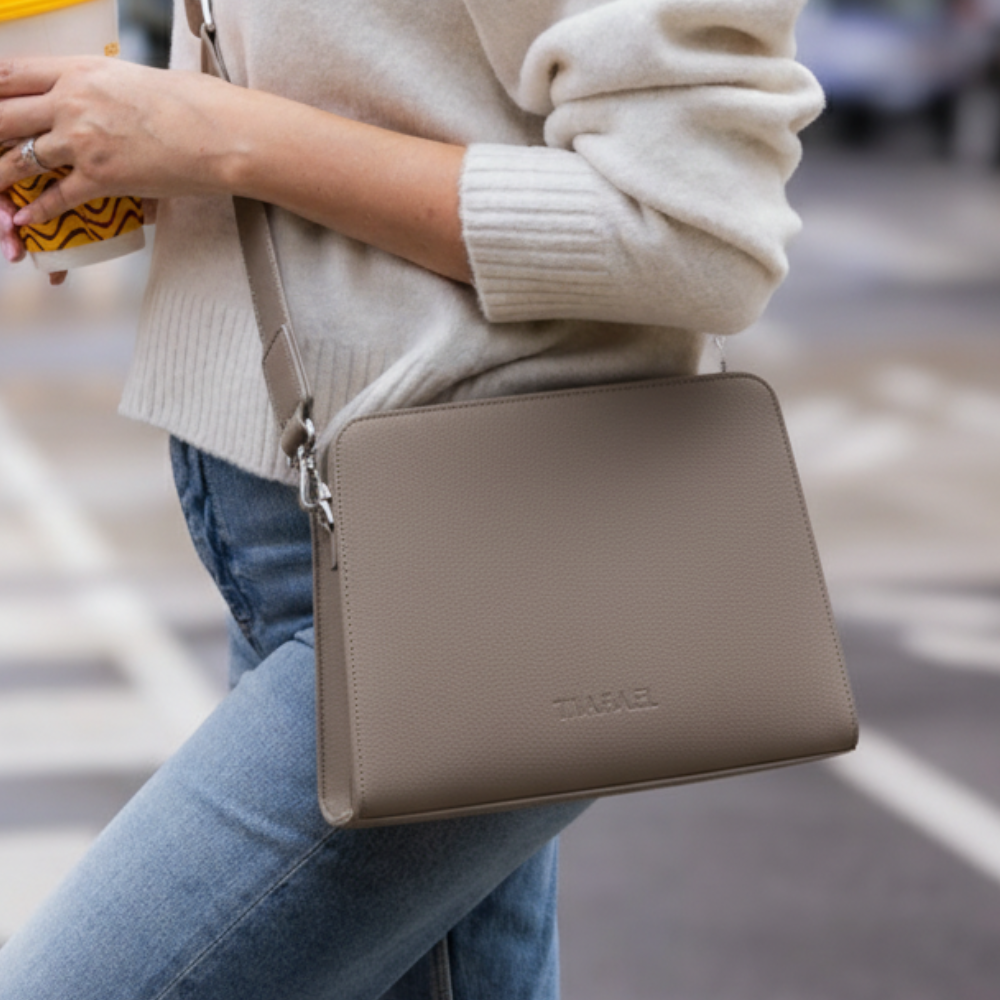 Stylish beige anti-theft travel crossbody bag worn by a woman during city sightseeing