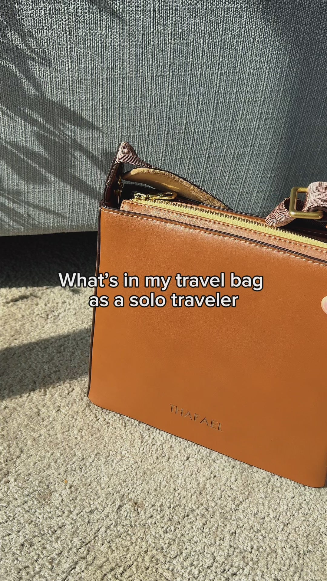 What’s in my travel bag video showing essentials like passport, cards, cash,, phone, sunglasses, camera, phone charger, and hand sanitizer inside a crossbody purse for women
